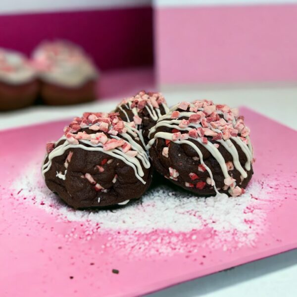 A pink plate with three chocolate covered cookies.