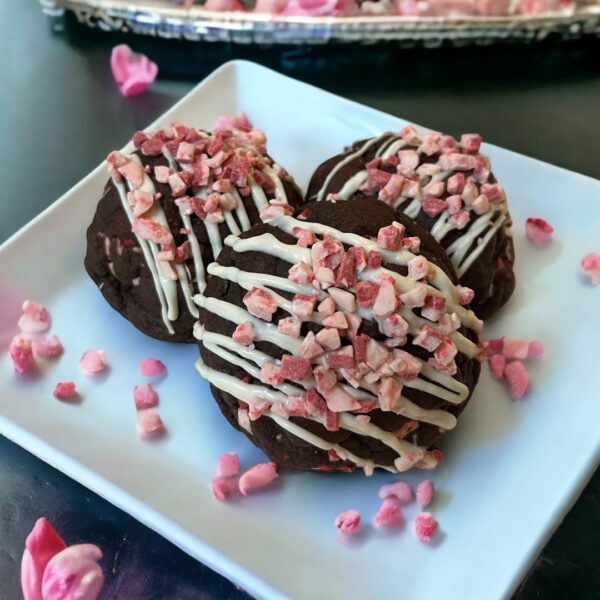 Three cookies on a plate with pink sprinkles.