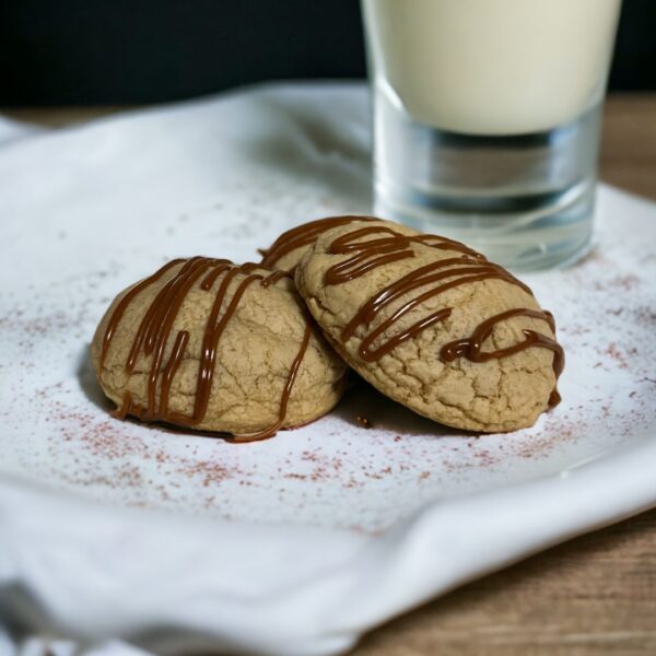 Two cookies on a plate next to a glass of milk.