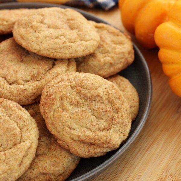 A bowl of cookies and some oranges on the table.