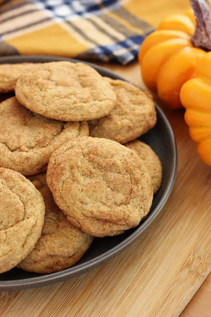 A bowl of cookies and some oranges on the table.