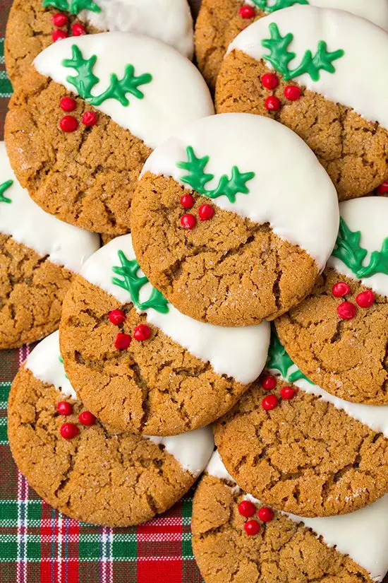 A pile of cookies with white frosting and red berries.