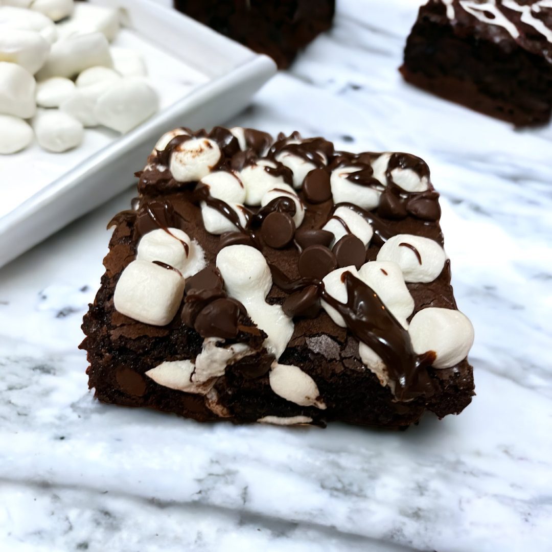 A square brownie with white chocolate and marshmallows on top.