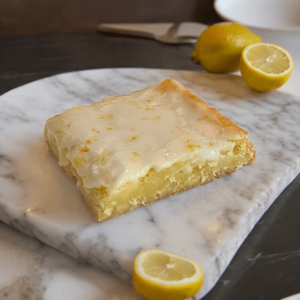 A piece of lemon cake sitting on top of a marble slab.