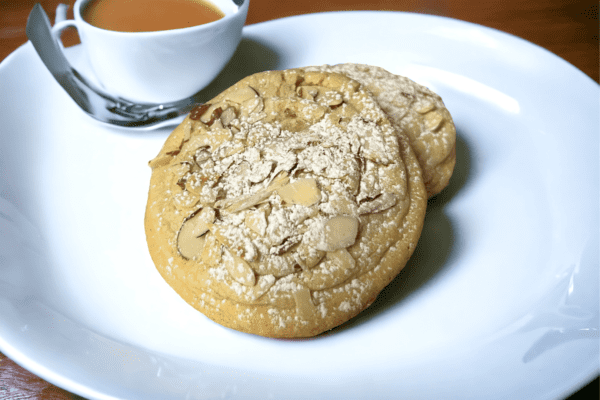 A cookie and cup of tea on a plate.