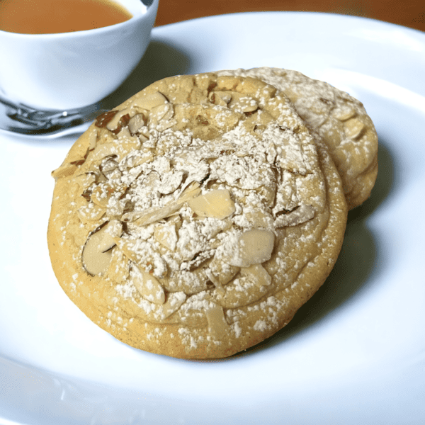 A cookie and cup of tea on a plate.