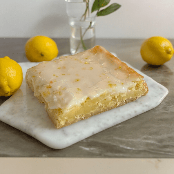 A square lemon cake sitting on top of a white plate.