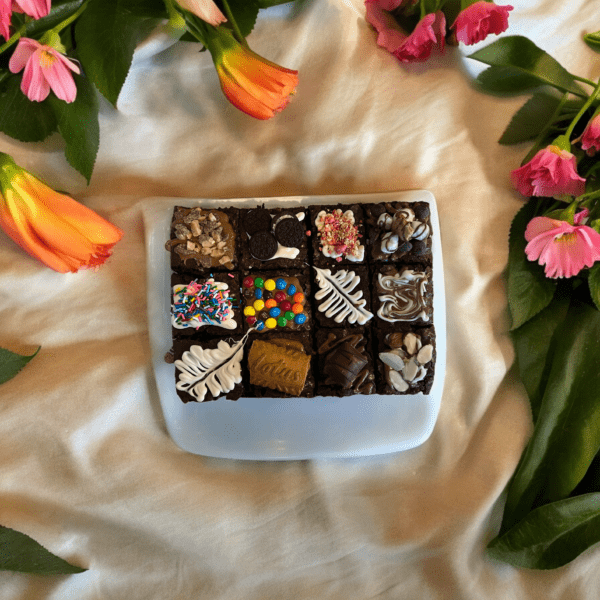 A box of chocolates surrounded by flowers on the table.