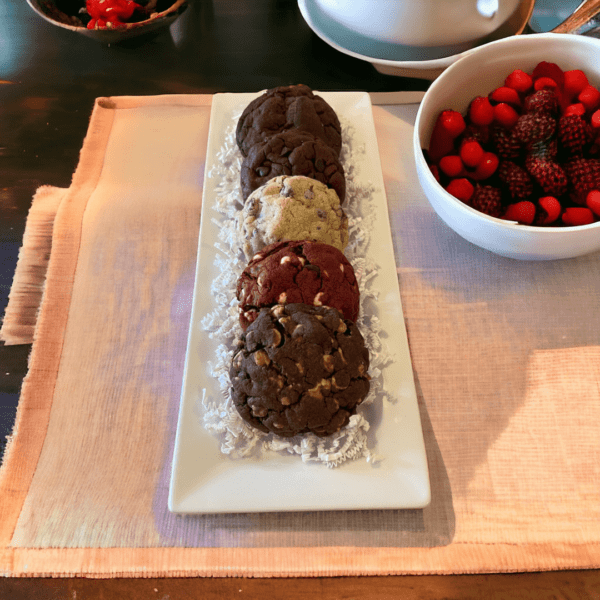 A plate of cookies and raspberries on the table.