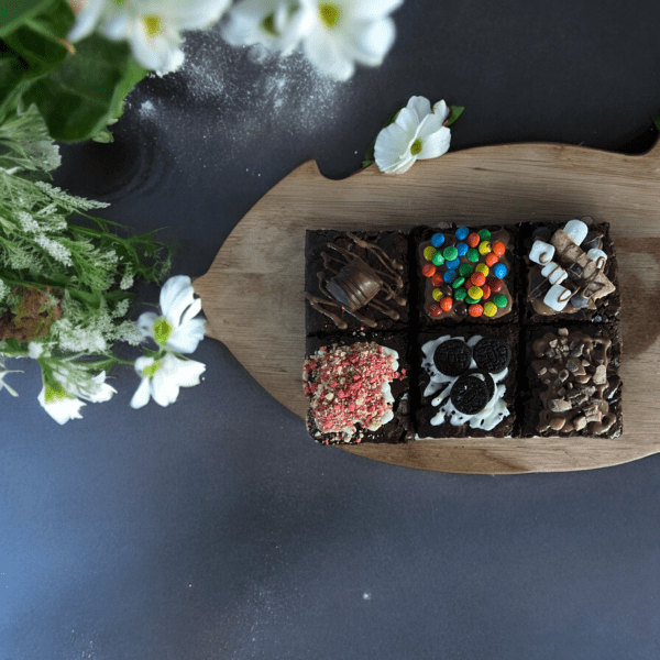 A wooden tray with six different types of brownies.